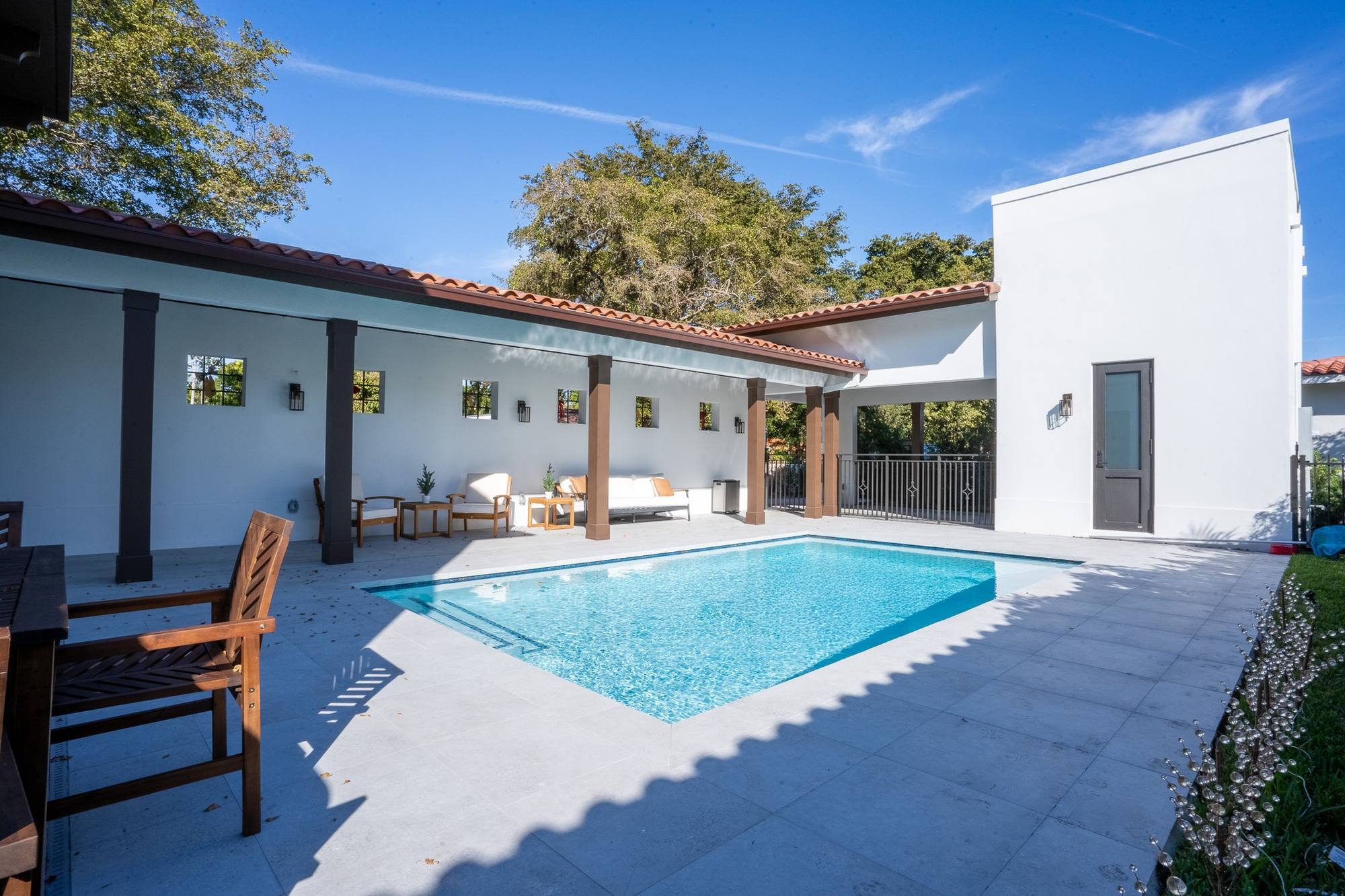 A pool beside a covered loggia with dark wood columns, Coral Gables