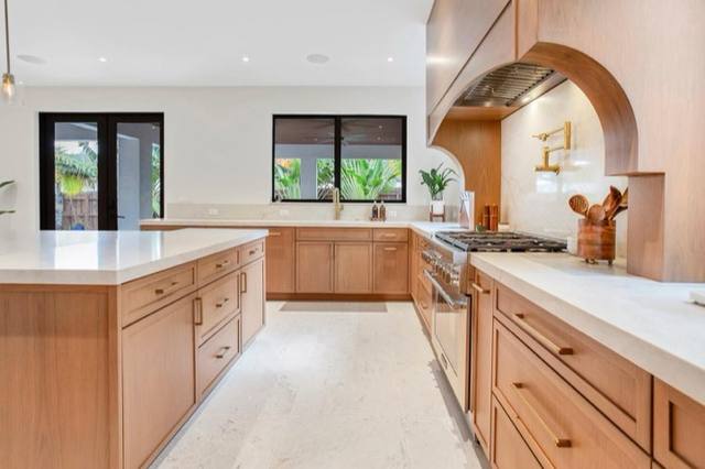 Kitchen with warm oak cabinets, white stone counters, wall oven and arched niche