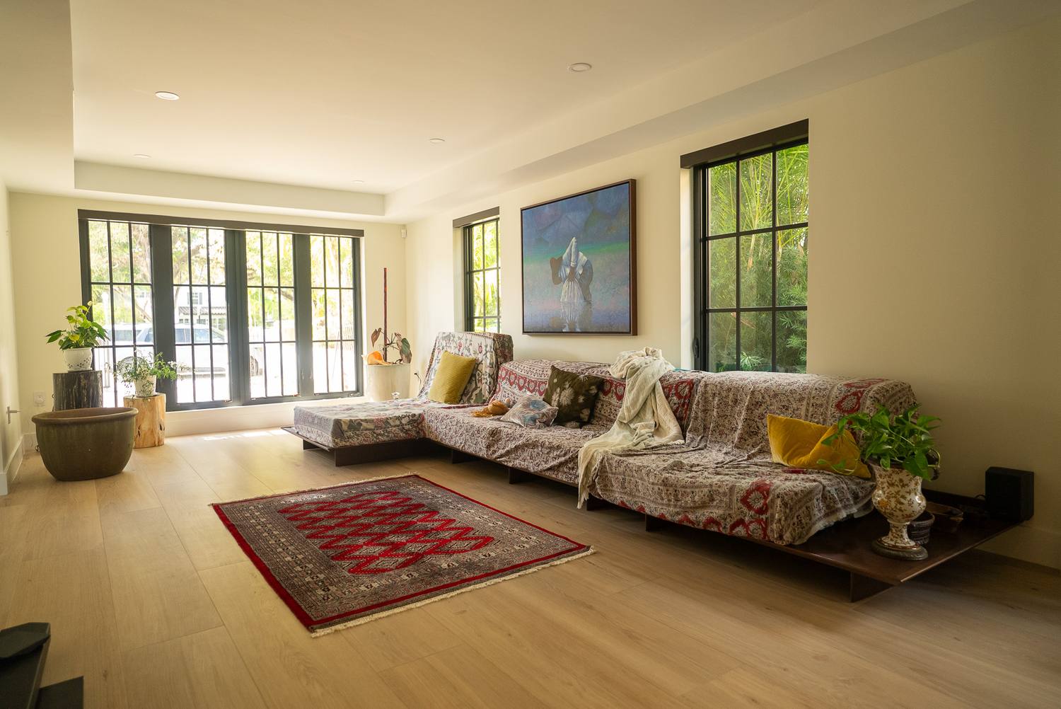 A living room with a low sectional, a red rug and tall windows