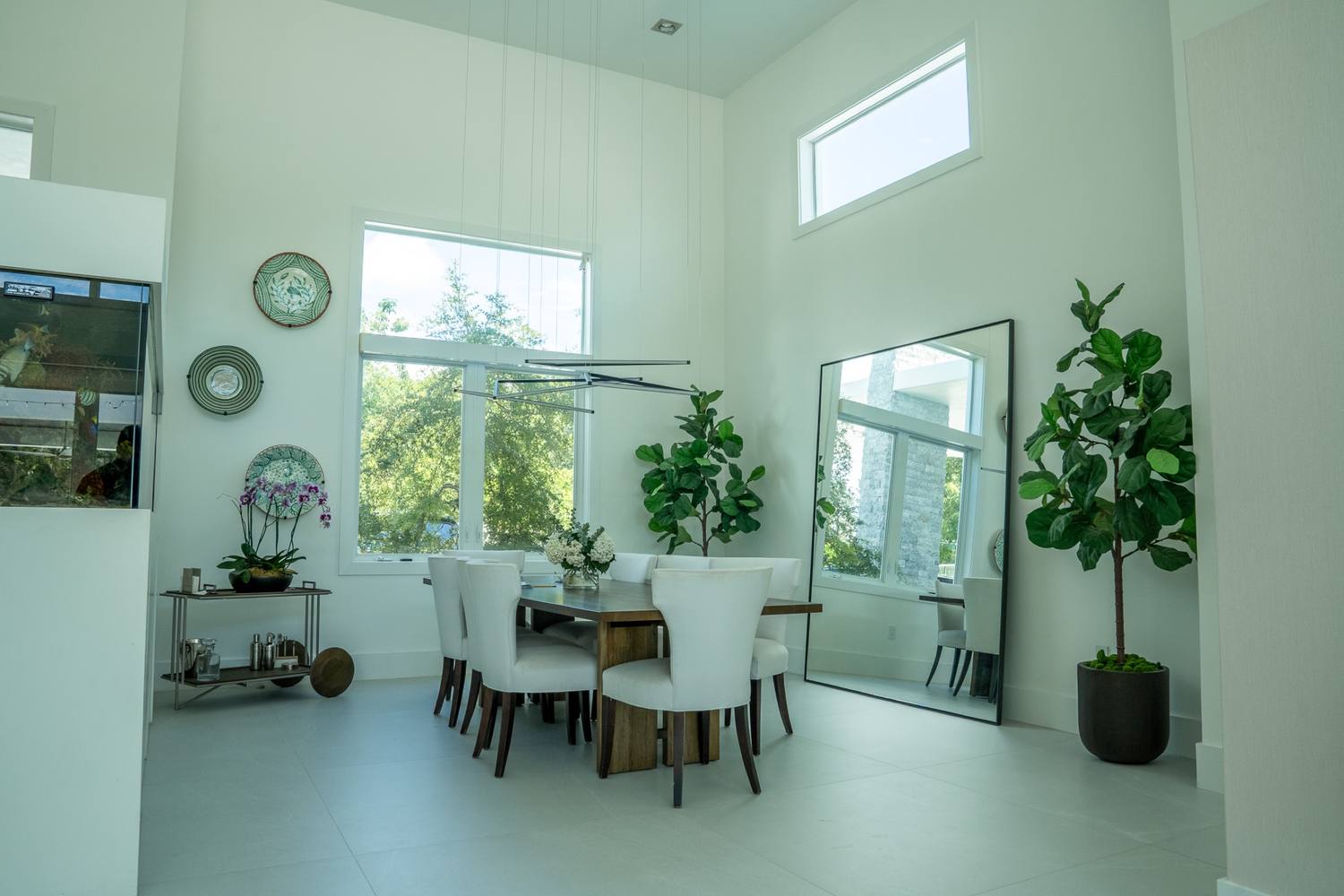 Dining room with white chairs under clerestory windows and a mirror leaning on the wall
