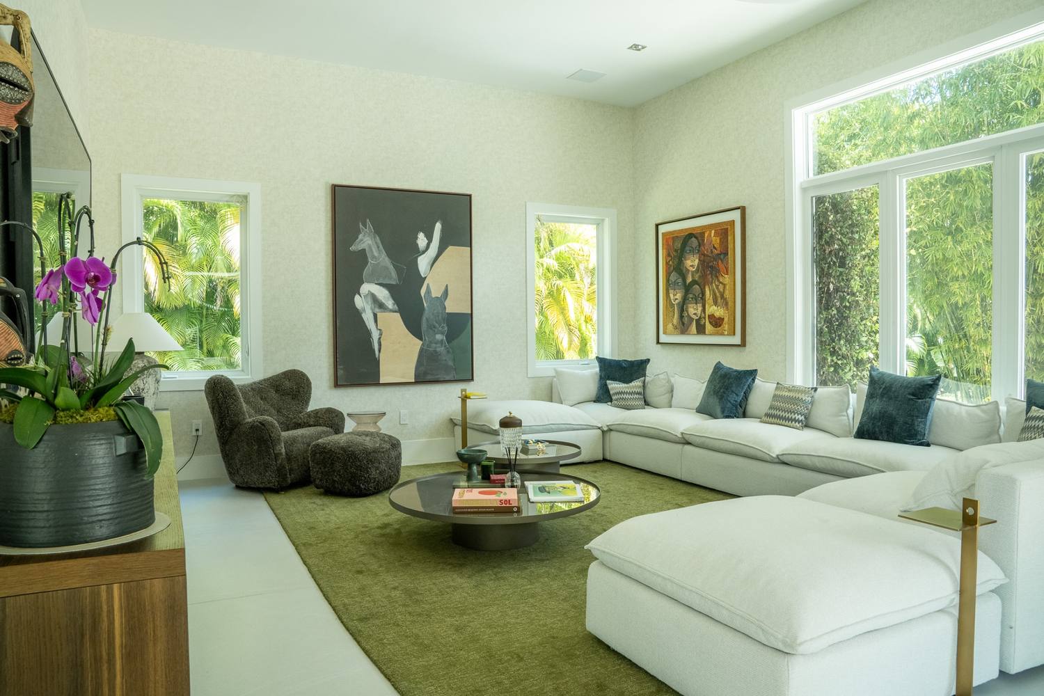 Family room with a white sectional, a green rug and art on the walls