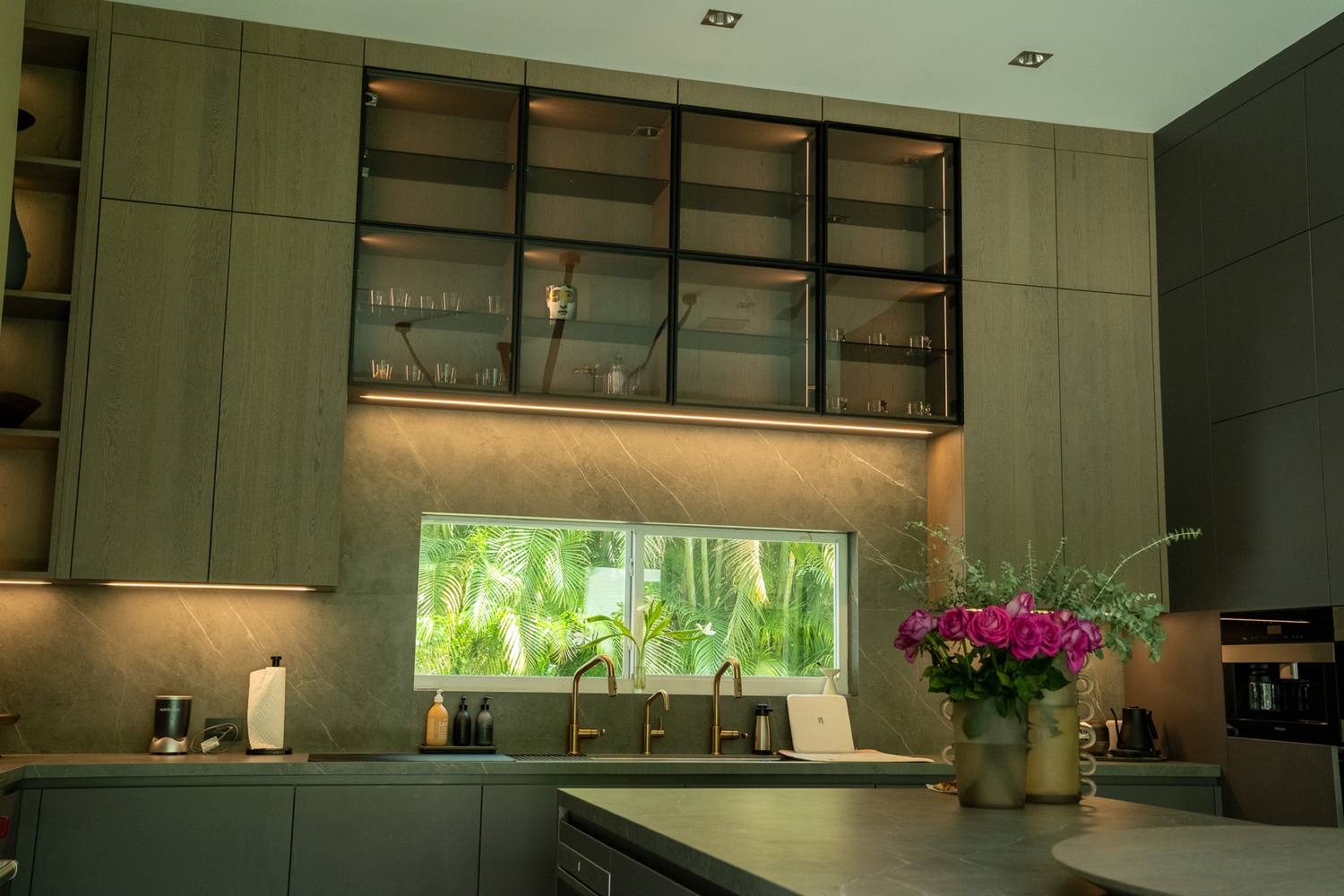Kitchen with dark cabinetry, a lit backsplash and a window over the counter