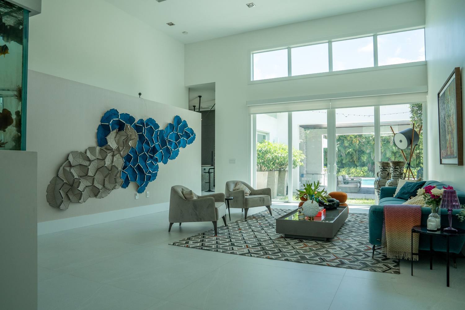 Double-height living room with a blue and white wall sculpture and a teal sofa