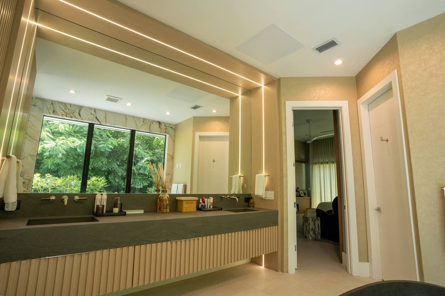 Floating vanity under a wide mirror framed with light strips