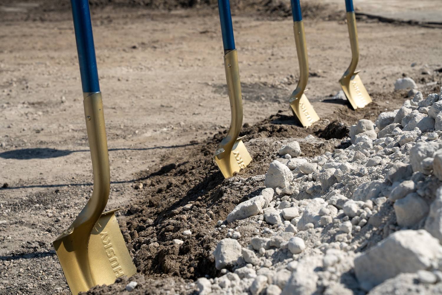 Gold groundbreaking shovels standing in the site fill