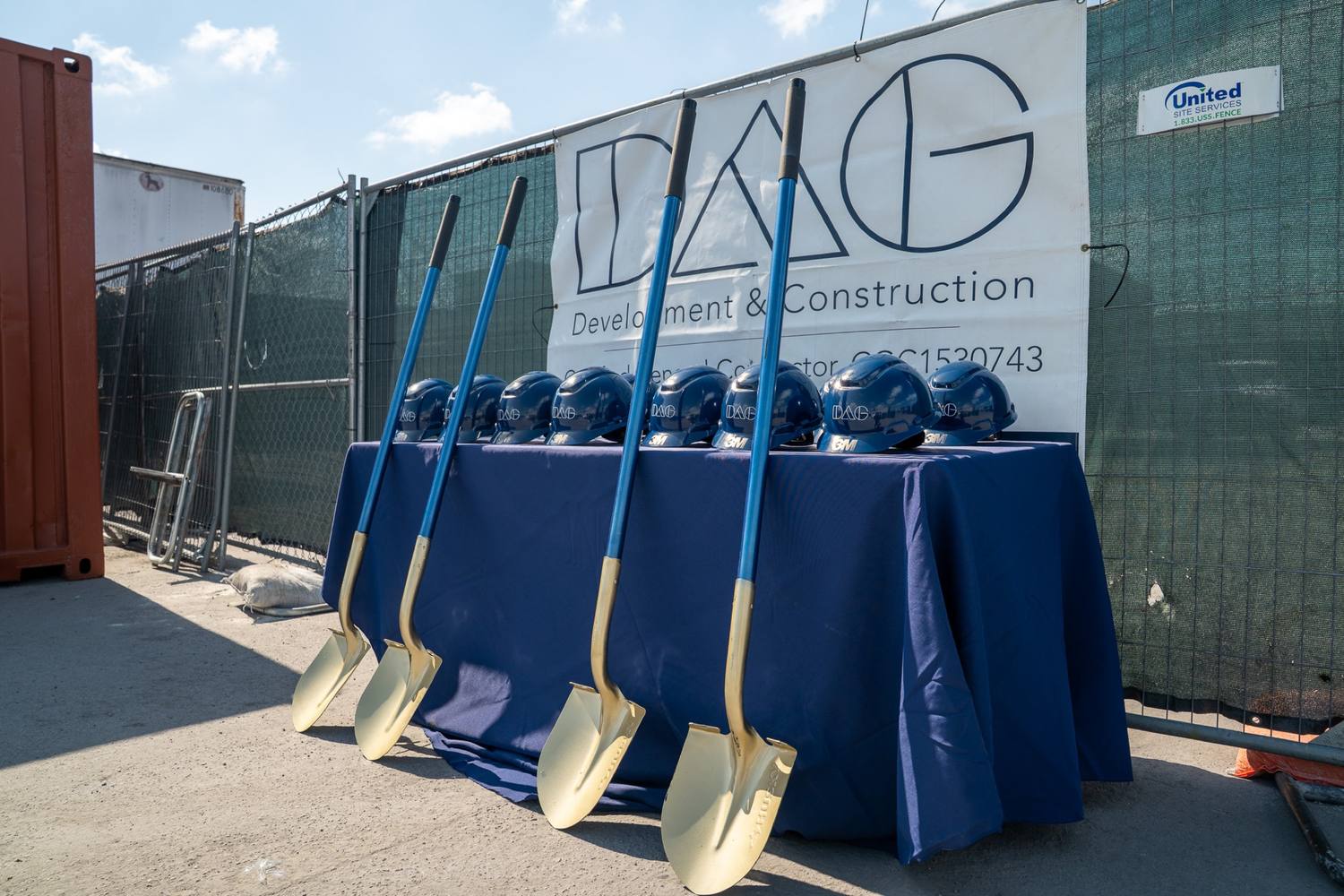 Groundbreaking table with hardhats and shovels under the DAG banner