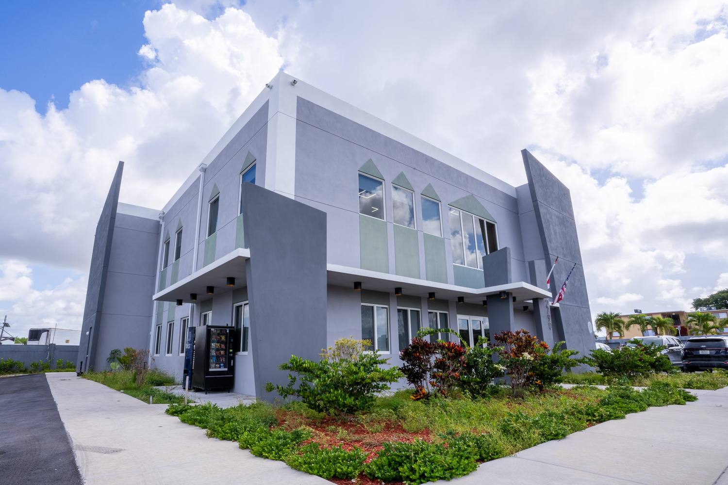 The office building from the corner, angled wing walls and a second-floor balcony