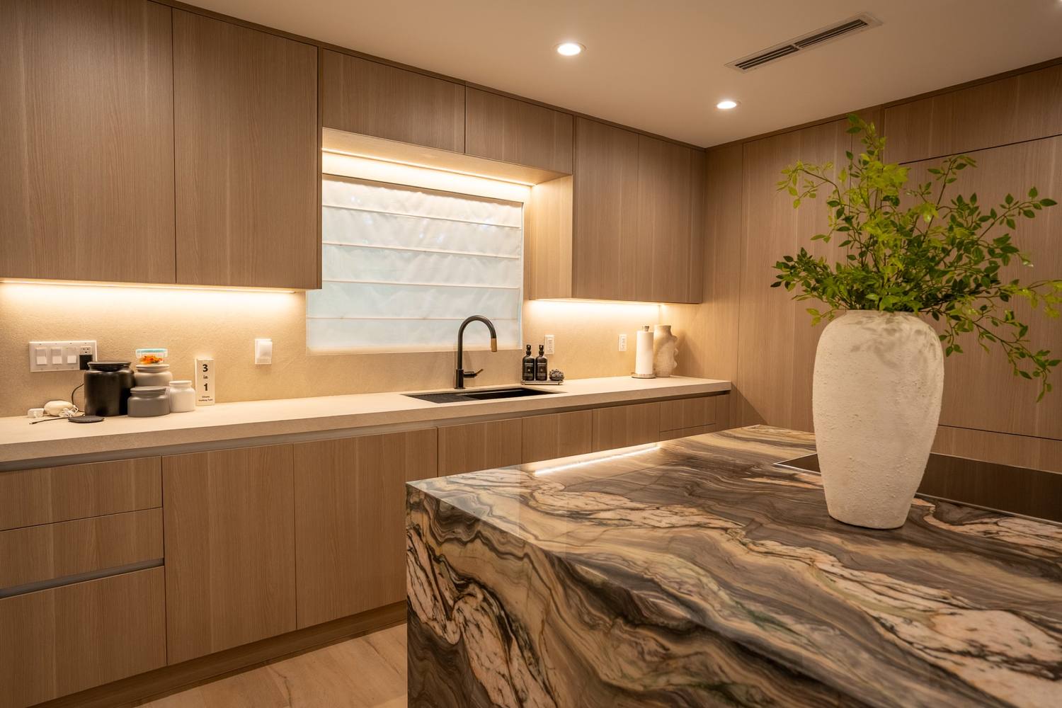 Kitchen island in stone with a waterfall edge and a vase
