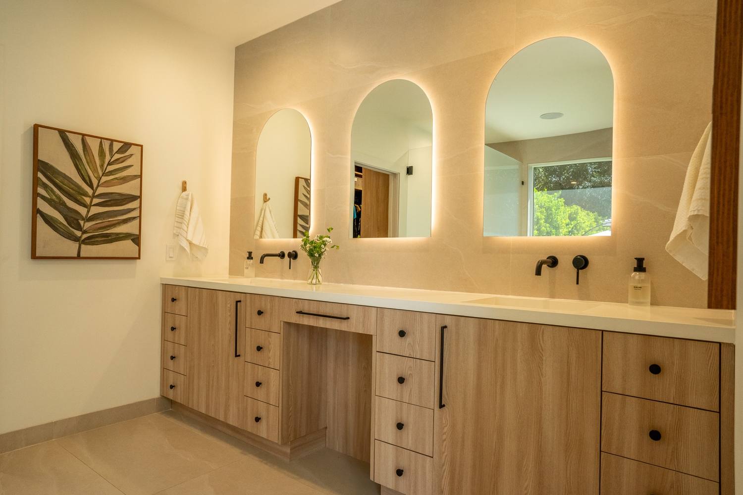 Primary bathroom with three arched mirrors over an oak double vanity