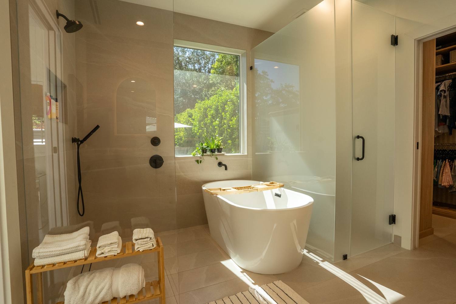 Primary bathroom with a freestanding tub under a window beside a glass shower