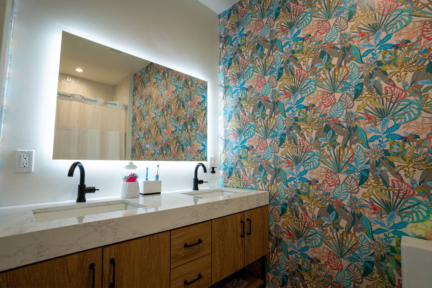 Powder room with a wallpapered wall, a lit mirror and an oak vanity